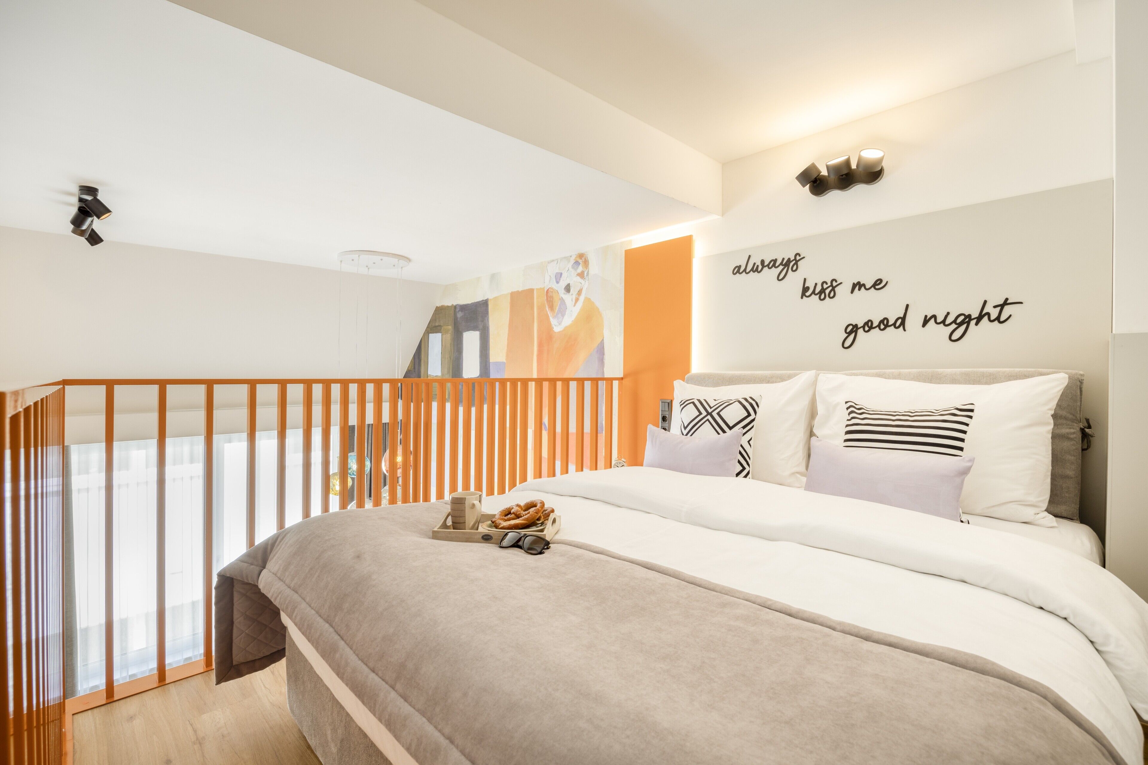 A modern bedroom with a bed, a wall with a message, a window, and a balcony.