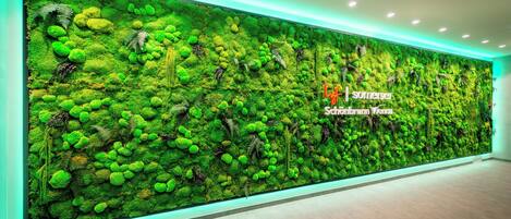 A wall with a green moss and plant wall design, a sign reading "Somerset," and a tiled floor.