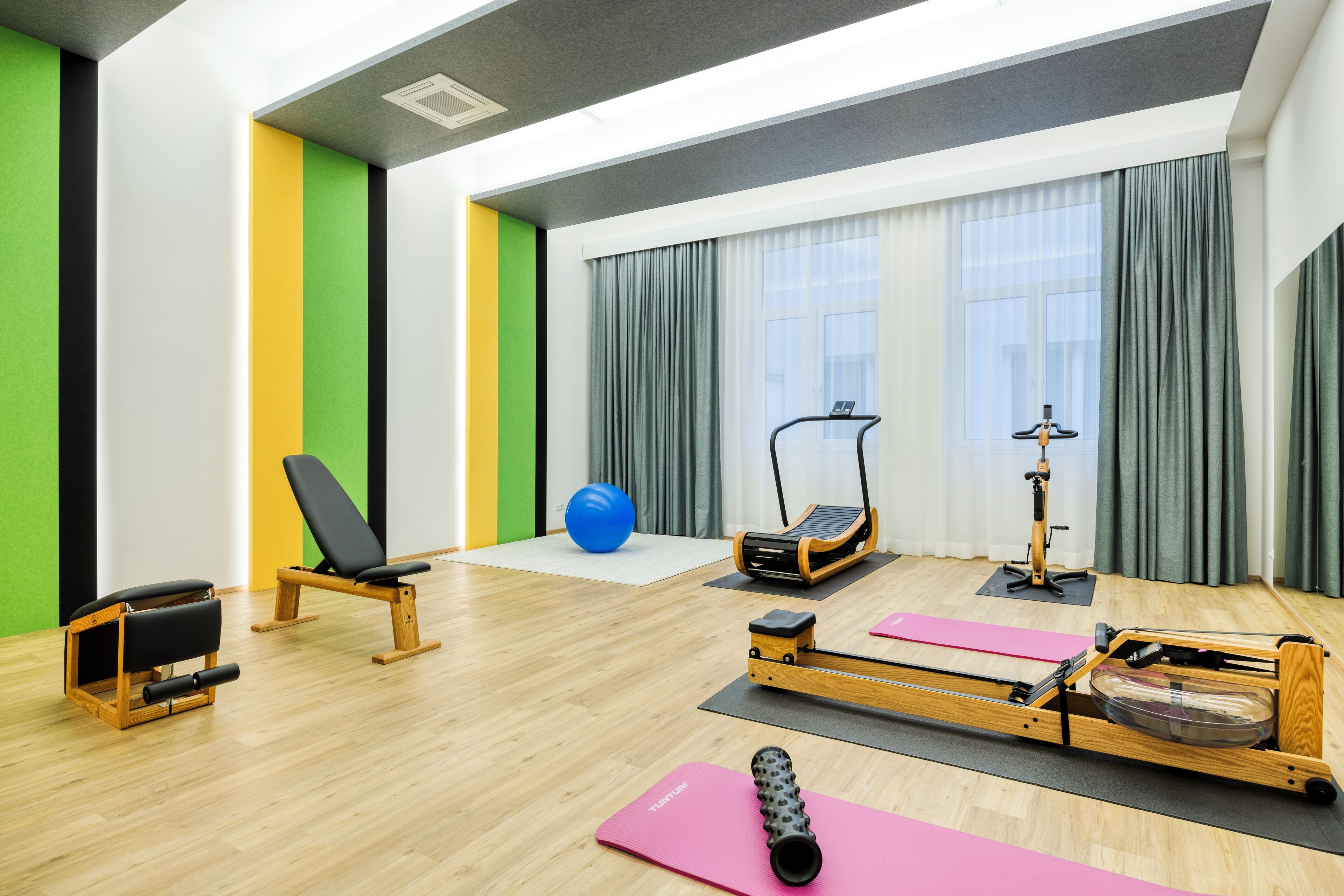 A fitness room with exercise equipment, a blue exercise ball, and a rowing machine.