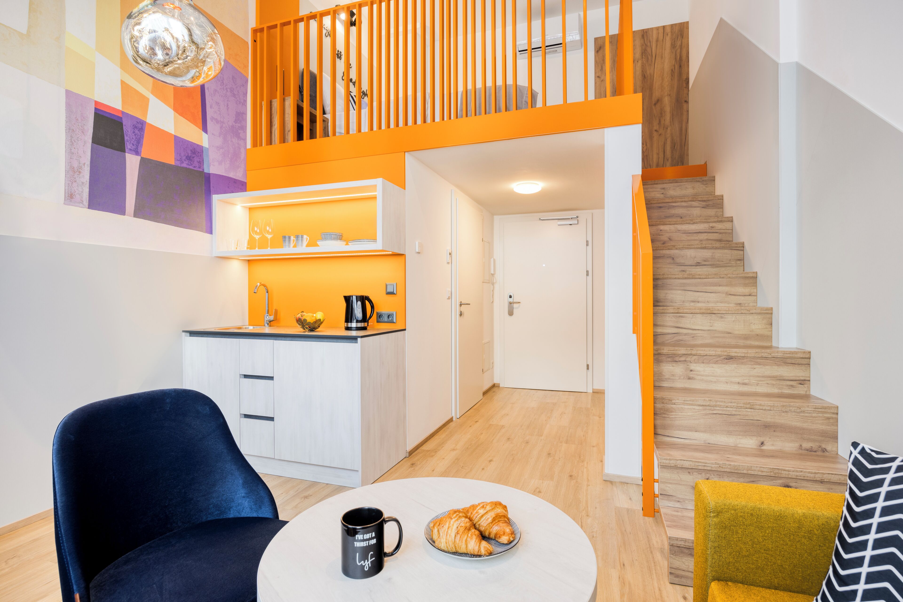 En modern lägenhet med kök, matplats och en trappa.