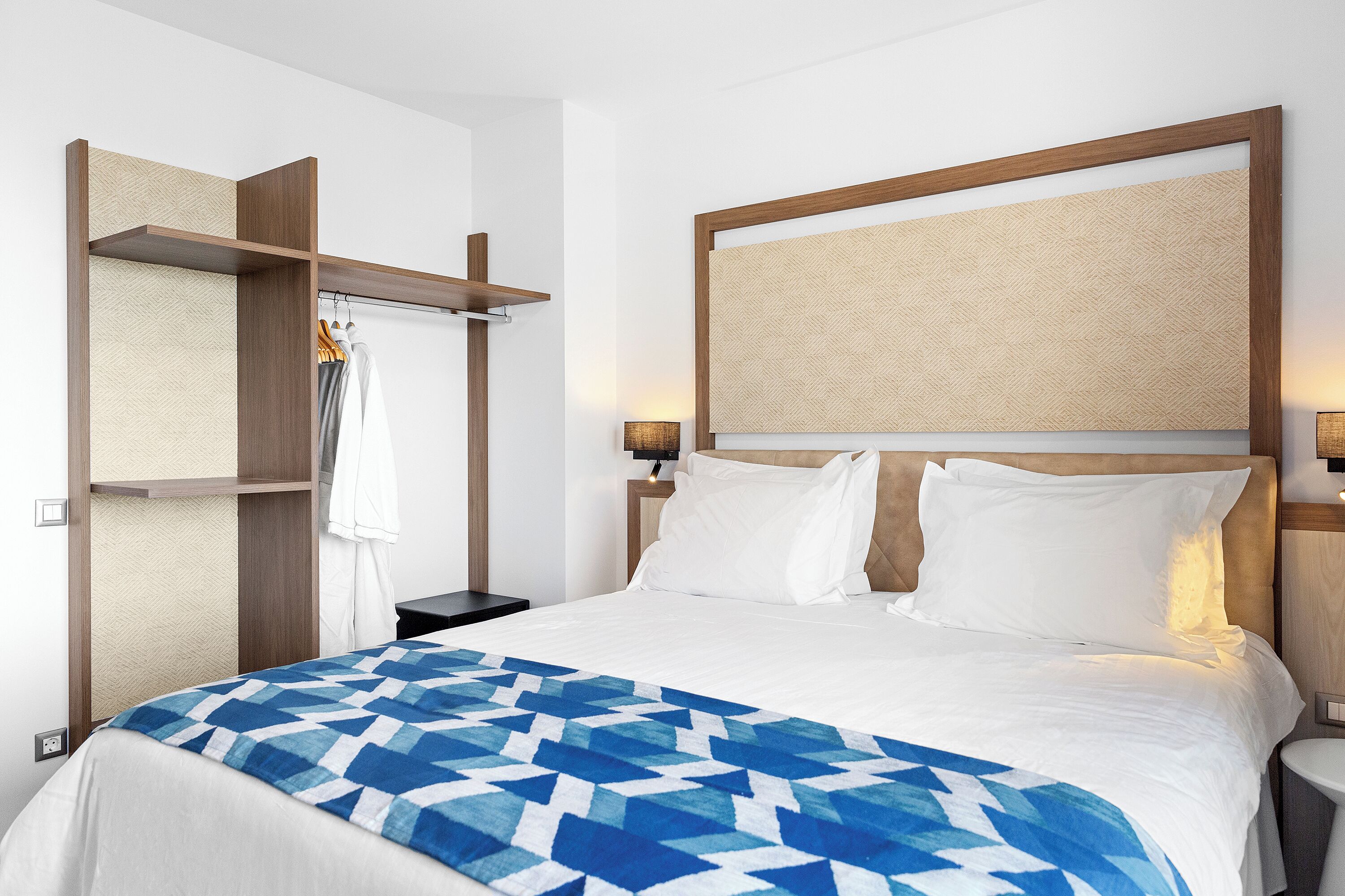 Habitació d'hotel amb un llit, un armari i una taula de nit.