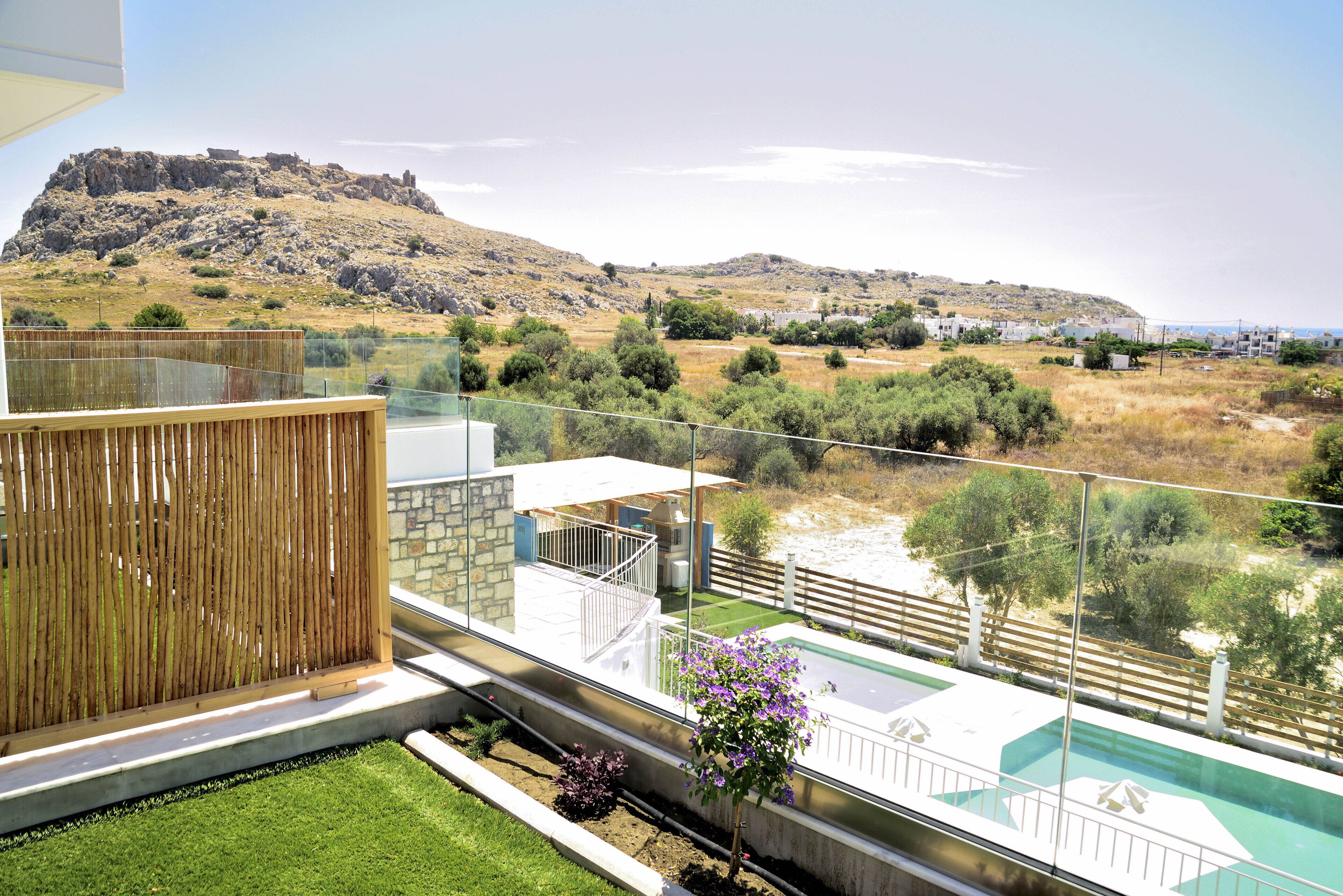 A modern outdoor terrace with a view of a hill and a pool.