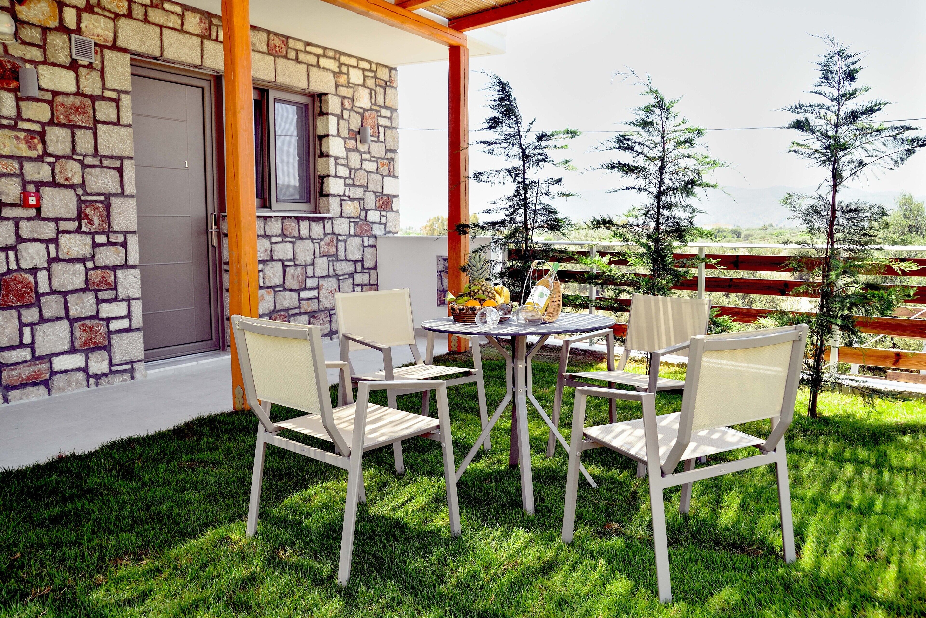 Une terrasse avec un mur en pierre, une porte et une table entourée de chaises.