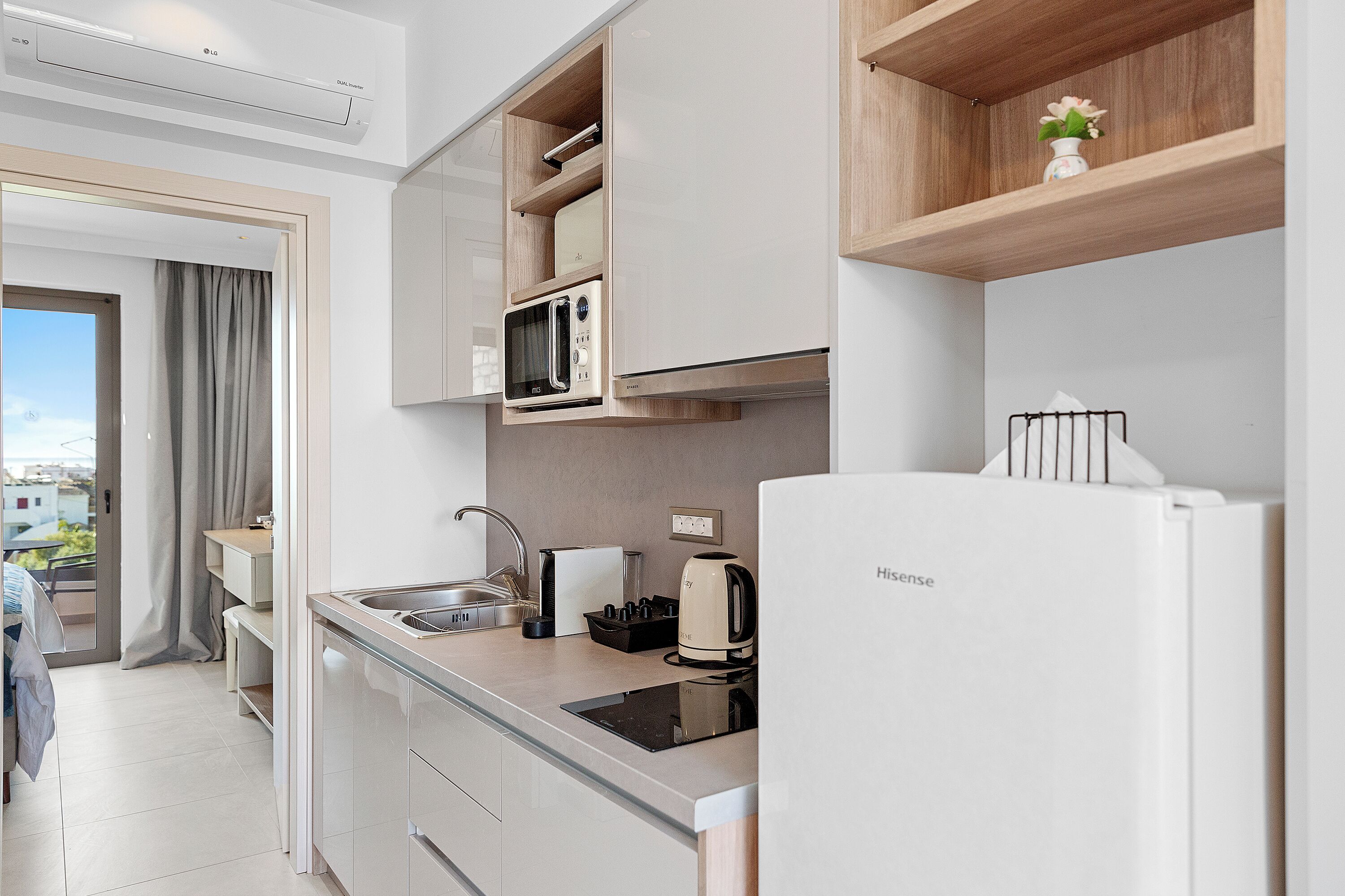 A modern kitchen with built-in appliances, a sink, and a compact refrigerator.