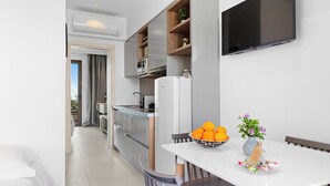 Una cocina moderna con horno empotrado, microondas y refrigerador. Hay una mesa de comedor con un tazón de naranjas y un jarrón de flores.