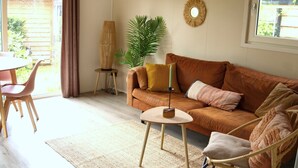 A living room with a brown sofa, a round coffee table, and a dining area with a table and chairs.