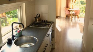 A kitchen with a gas stove, sink, and cabinets. There is a dining area with a table and chairs.