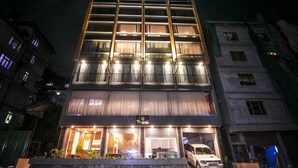 Un hôtel à la façade moderne, doté de nombreux balcons et d’une base en pierre.