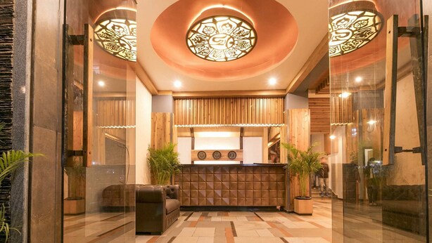 Un espace d’accueil au design moderne, comprenant un comptoir d’accueil en bois, un coin salon et des panneaux muraux décoratifs.