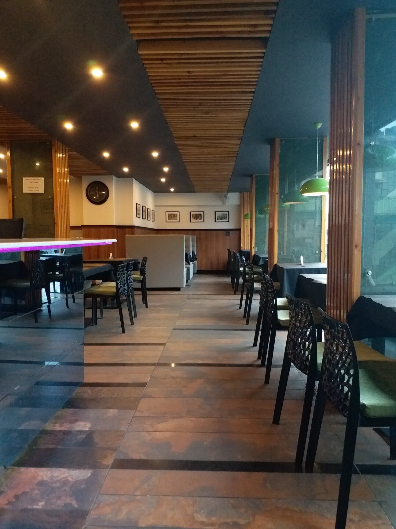 A restaurant with a long counter, wooden ceiling, and tiled floor.