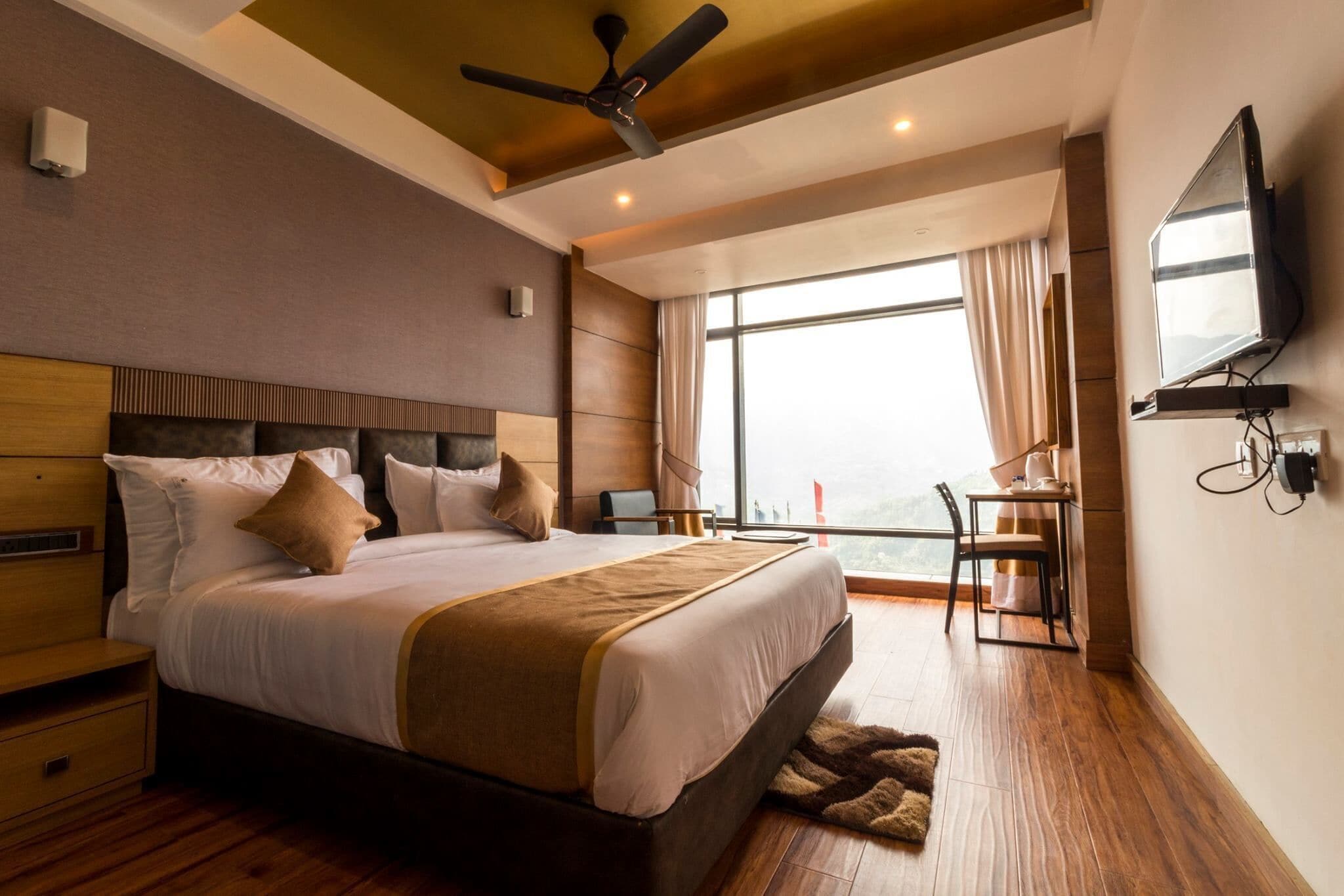 A modern hotel room with a large bed, a desk, and a television.