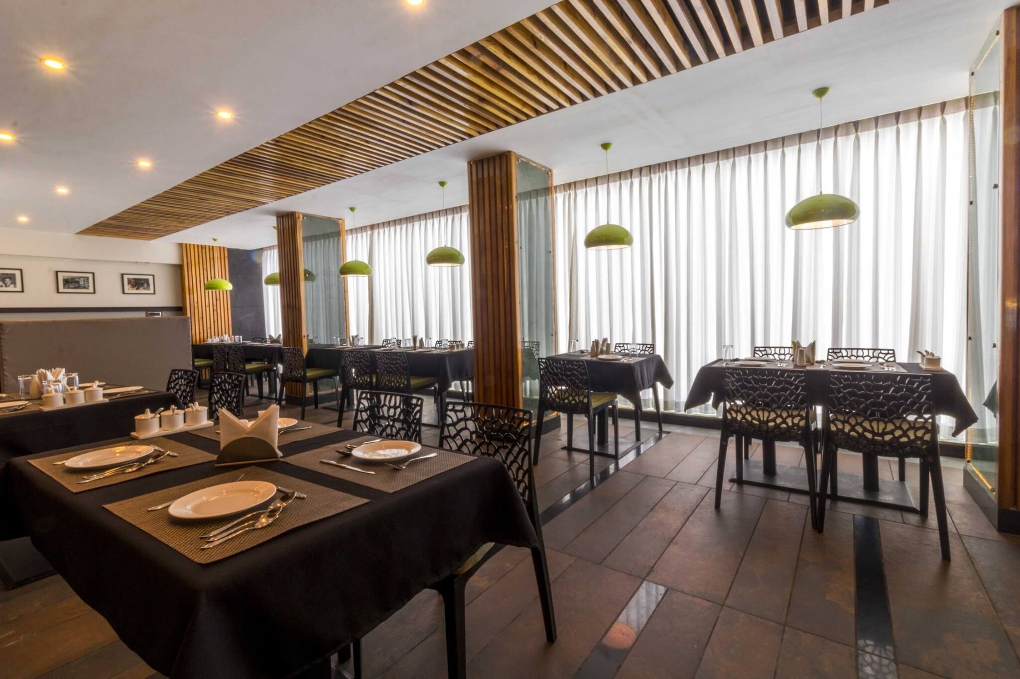 A restaurant with multiple tables set for dining, featuring black tablecloths and metal chairs.