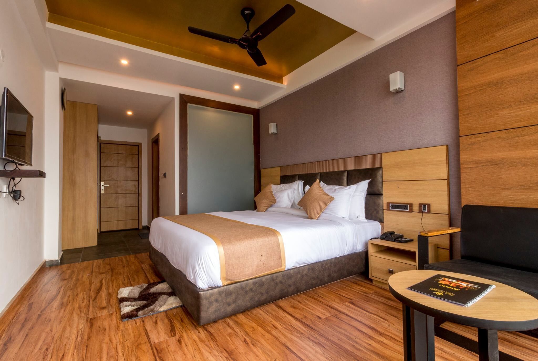 A hotel room with a bed, bedside table, chair, and a ceiling fan.