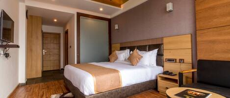 A hotel room with a bed, bedside table, chair, and a ceiling fan.