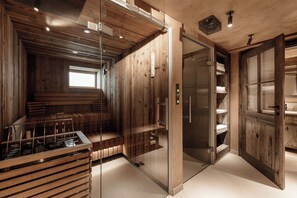 A modern interior with wooden paneling, a sauna, and a glass-enclosed shower area. - Chalet Cecilia by MYALPS (Soelden)