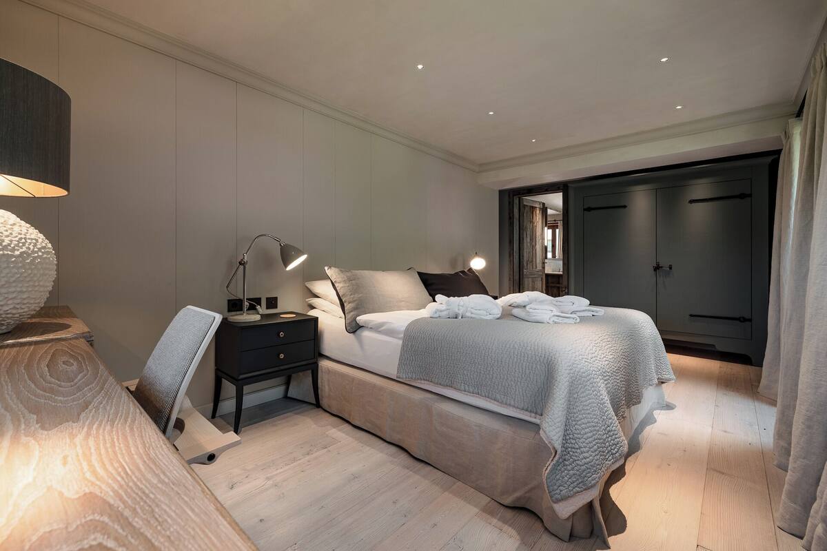 A modern bedroom with a bed, bedside tables, a lamp, and a wardrobe.
