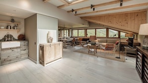 A spacious living area with a high ceiling, wooden beams, a skylight, and large windows offering views of the outdoors. - Chalet Cecilia by MYALPS (Soelden)