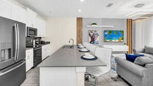 A modern kitchen with a central island, white cabinetry, and stainless steel appliances.