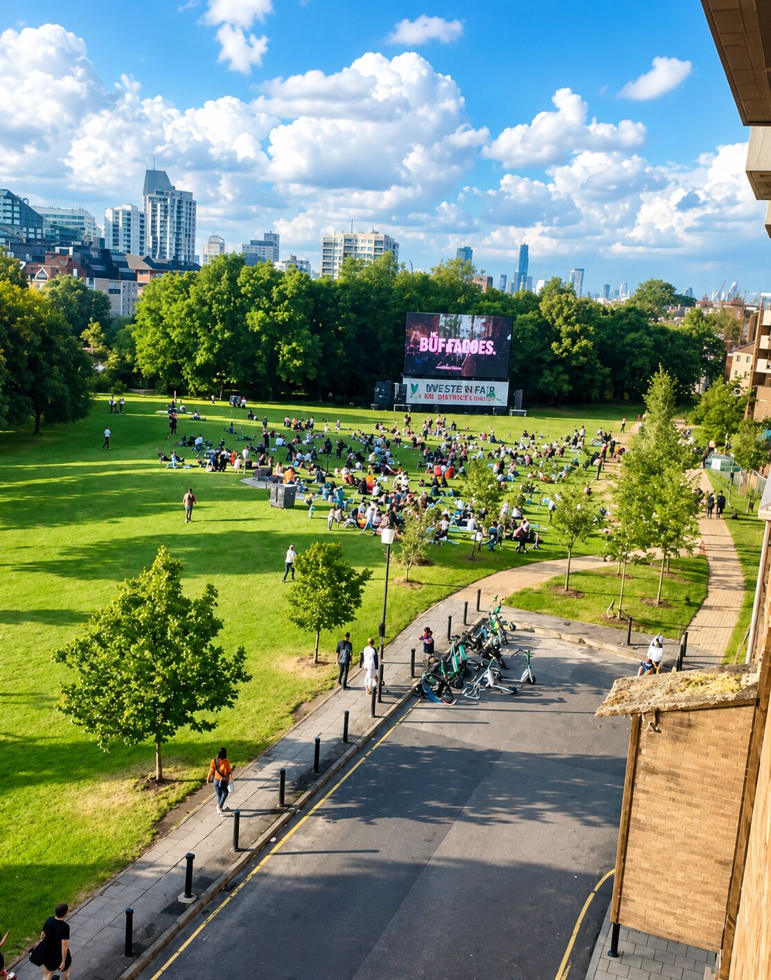 Een park met een groot reclamebord, bomen en een verharde looppad.