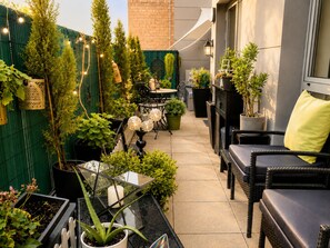 A patio area with outdoor furniture, potted plants, and string lights.