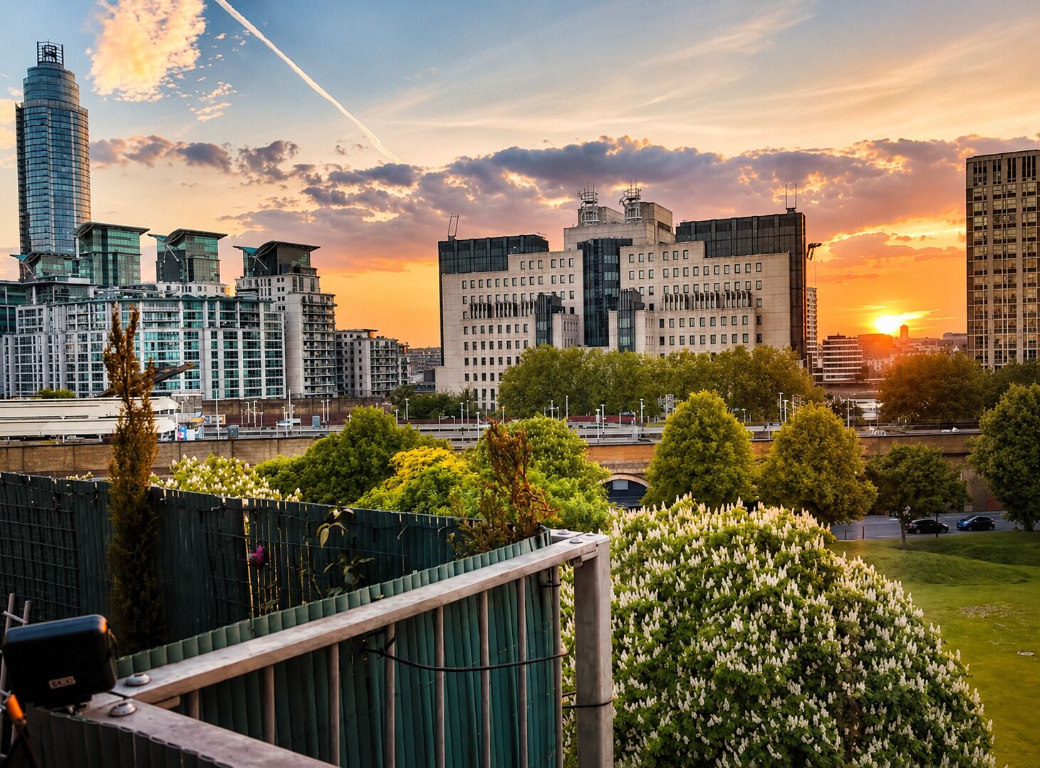 A cityscape with modern buildings, a river, and a sunset.