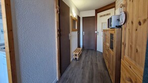 A narrow hallway with wooden cabinets and a microwave on the right. - Charming 2-room apartment for 4 in Arc 1800 (Les Arcs 1800)