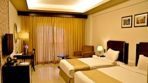Une chambre d’hôtel avec deux lits, un bureau avec une lampe, une chaise et une petite table.