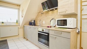 A compact kitchen with a microwave, oven, and coffee maker. - Appartementanlage Eldena Wohnung Nr. 10 (Mönchgut OT Lobbe)