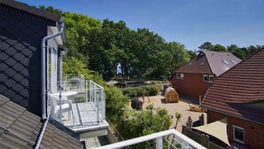 A residential area with a house featuring a balcony, a wooden playhouse, and a garden. - Appartementanlage Eldena Wohnung Nr. 10 (Mönchgut OT Lobbe)