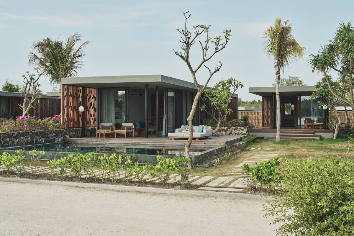 A modern resort with a pool, outdoor seating, and tropical landscaping.