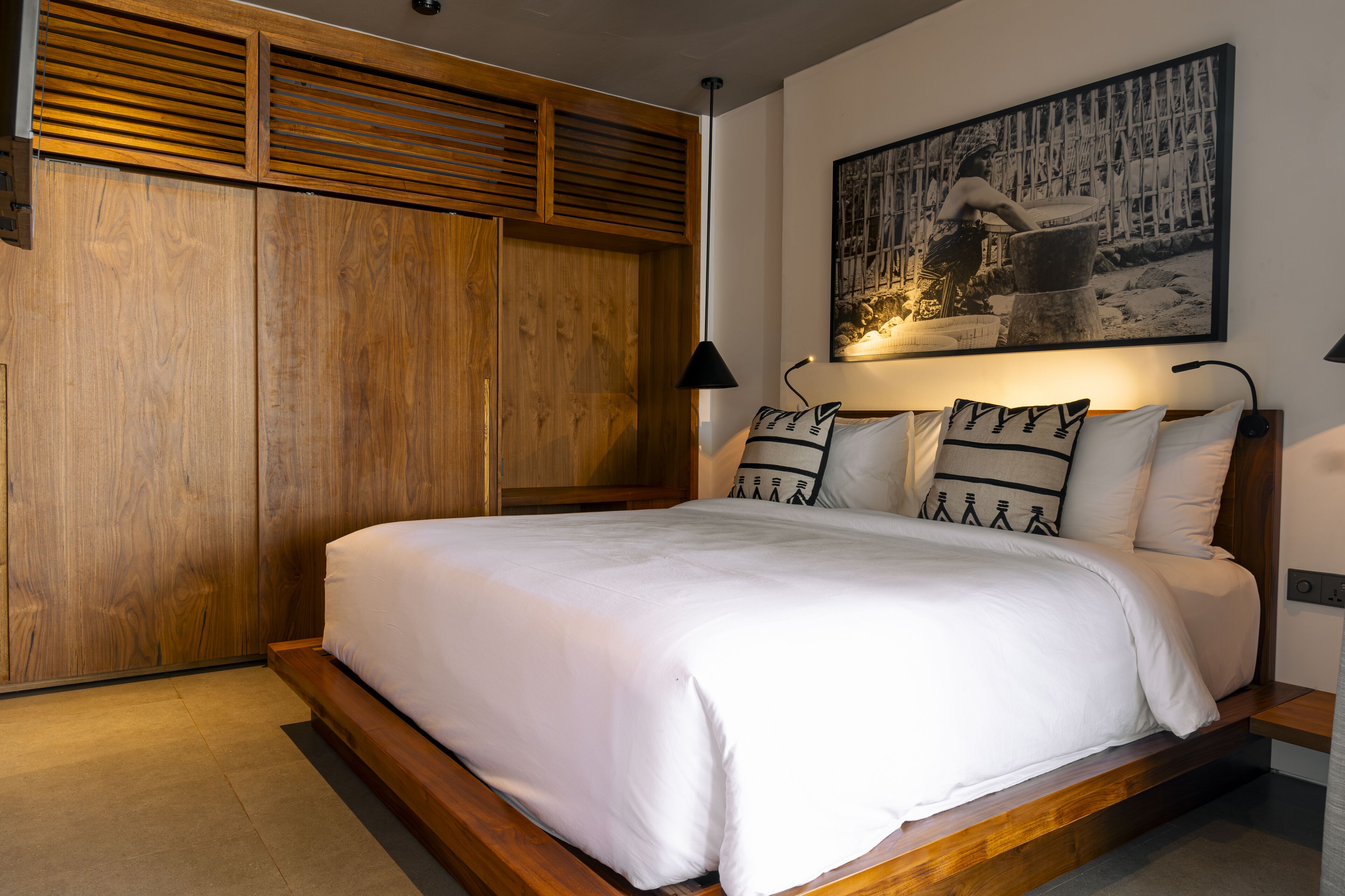 Un dormitorio con una cama grande, cabecera de madera y una obra de arte colgada en la pared.