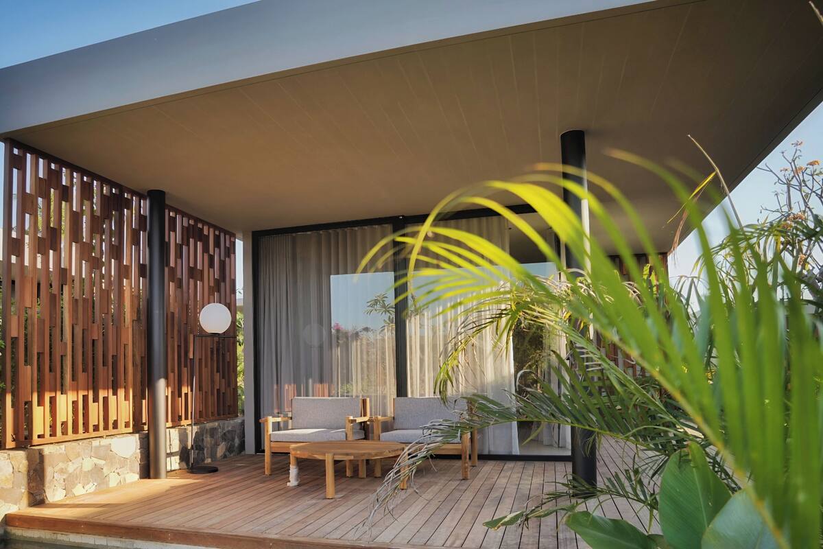 A modern outdoor seating area with wooden furniture and a stone wall backdrop.