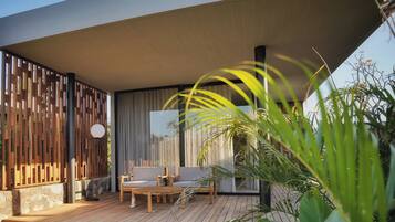 A modern outdoor seating area with wooden furniture and a stone wall backdrop.