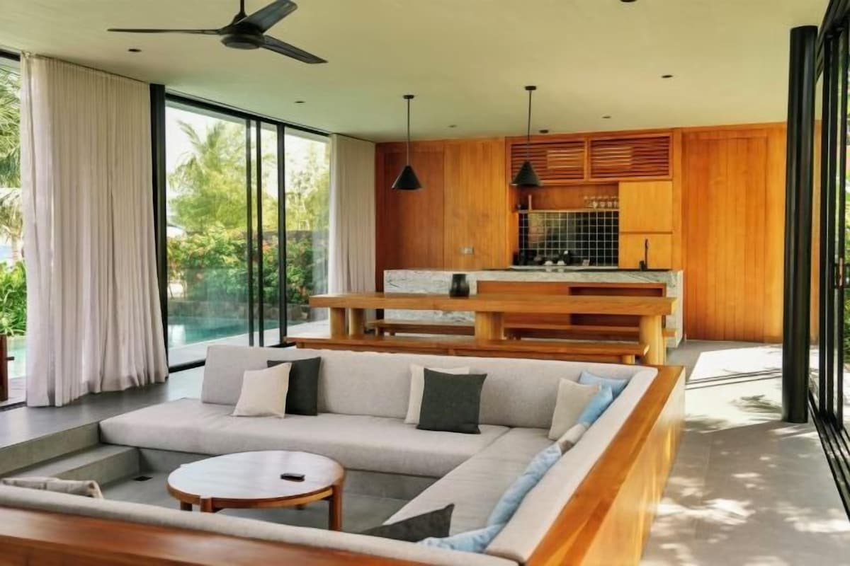 A modern living room with a sofa, a round coffee table, and a dining area with wooden furniture.