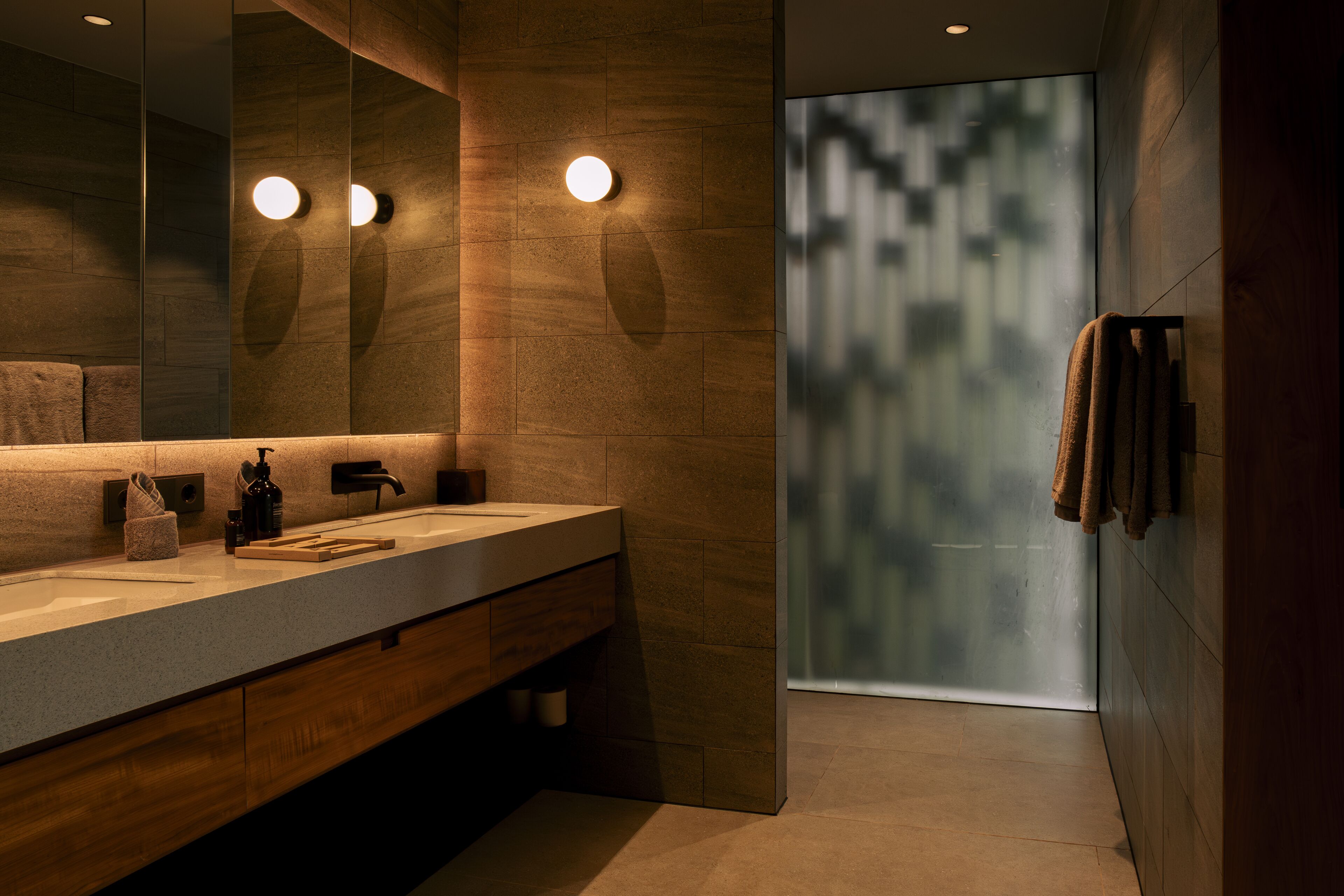 Ein modernes Badezimmer mit einem Holzkosmetikschrank, einem großen Spiegel und einer Duschkabine aus Glas.