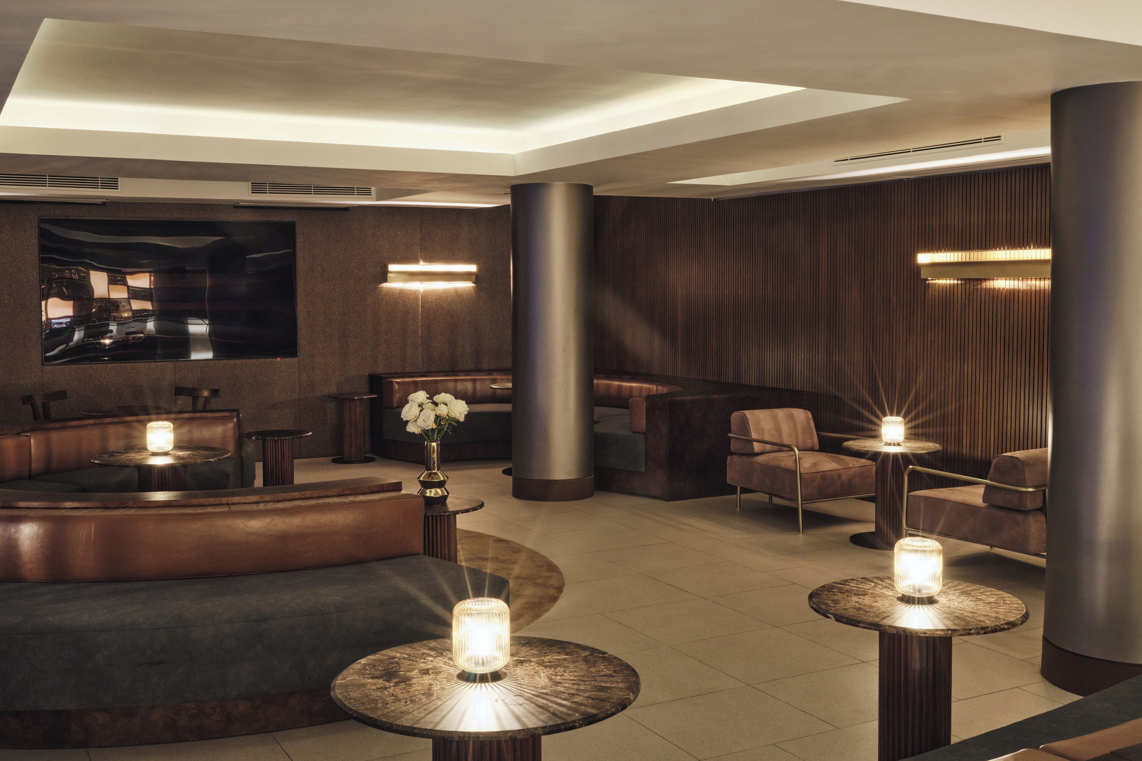 Una hall moderna con un'area salotto dalle linee curve, un grande schermo piatto e illuminazione d'ambiente.