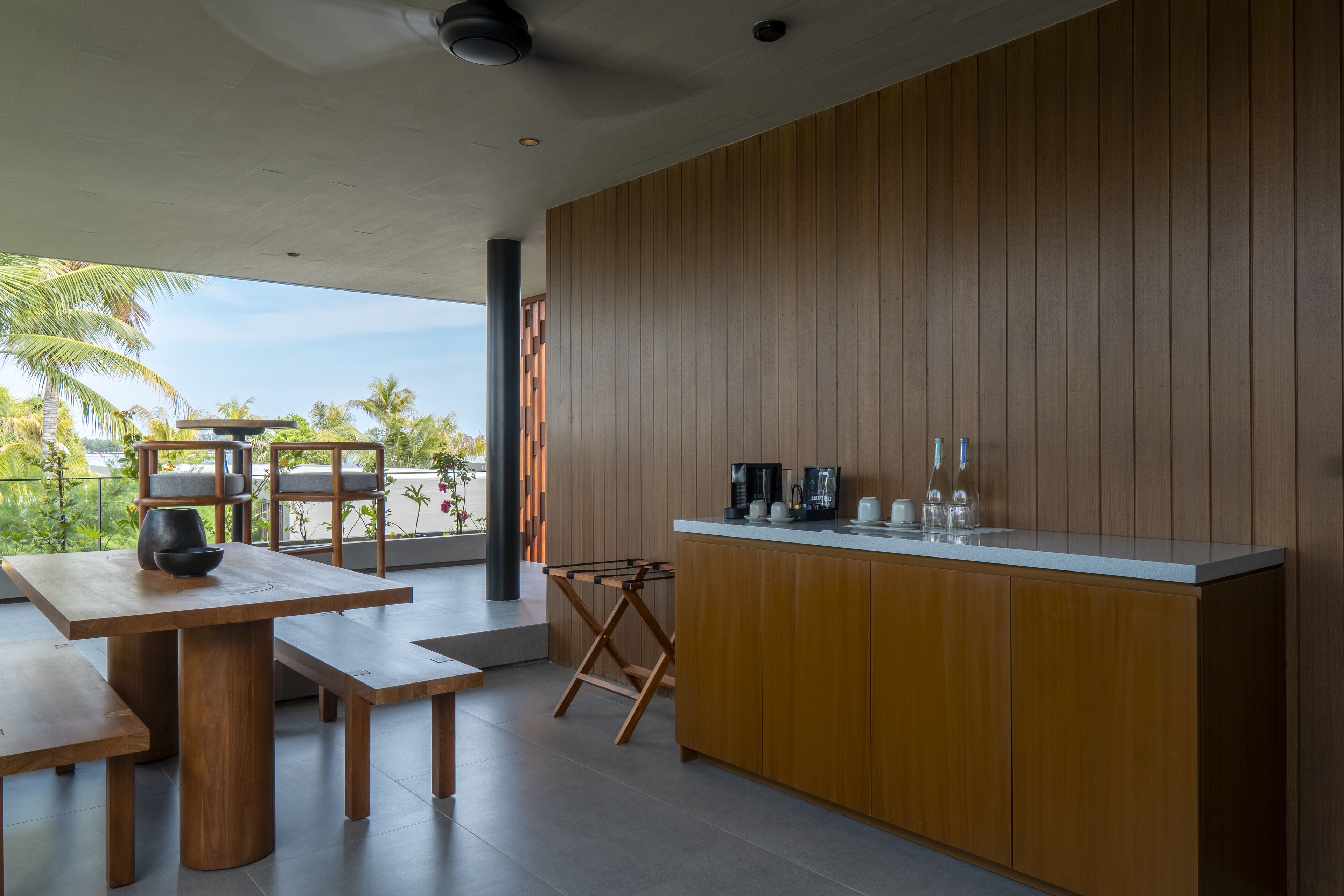 A modern kitchen with wooden cabinets, a countertop, and a dining area with a table and benches.