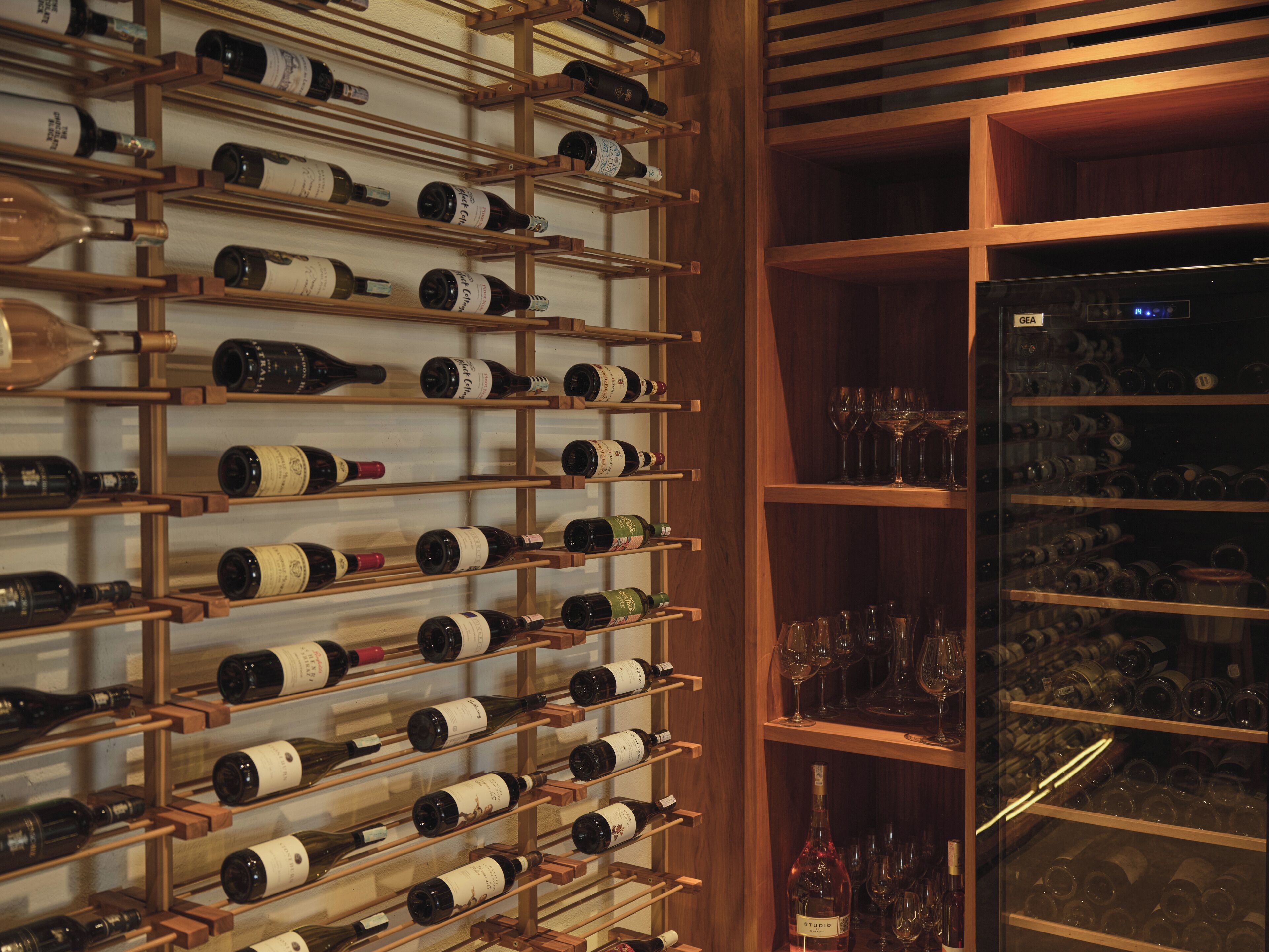 Una bodega con estanterías de madera que albergan botellas de vino y copas.