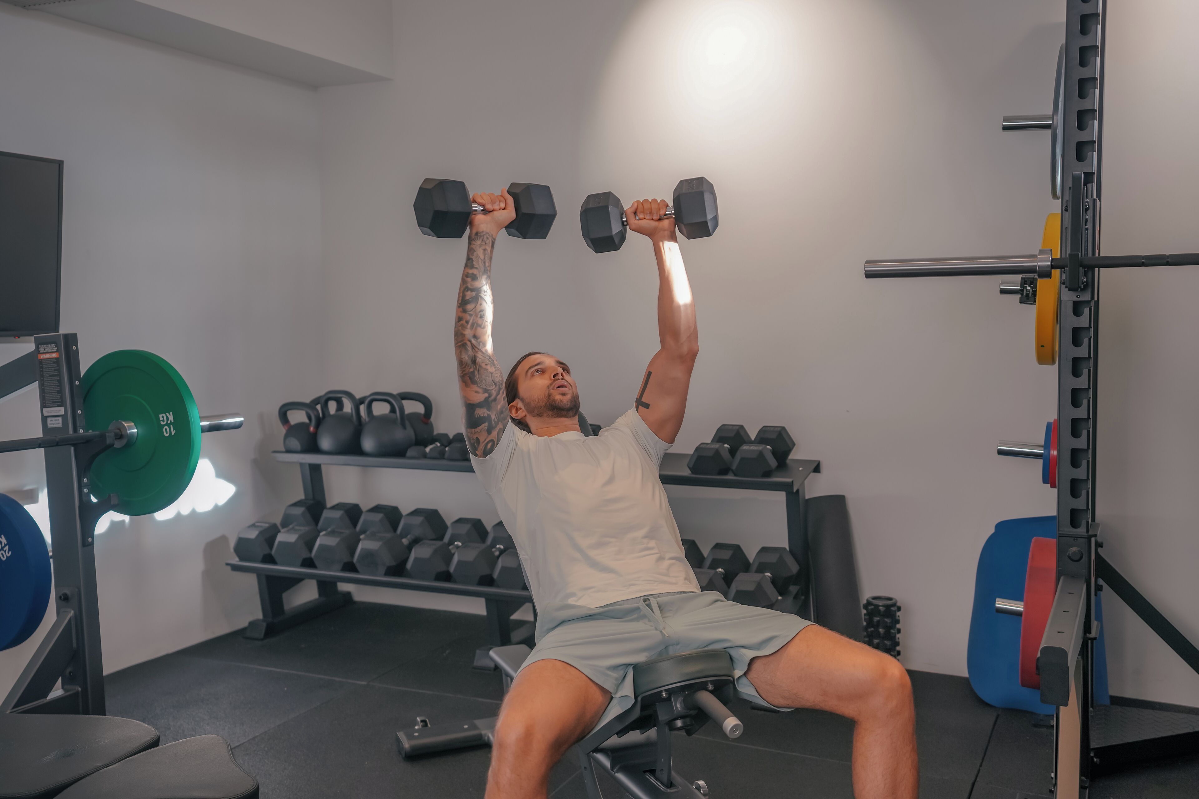 Une salle de sport équipée de matériel de musculation, de bancs et d’haltères.