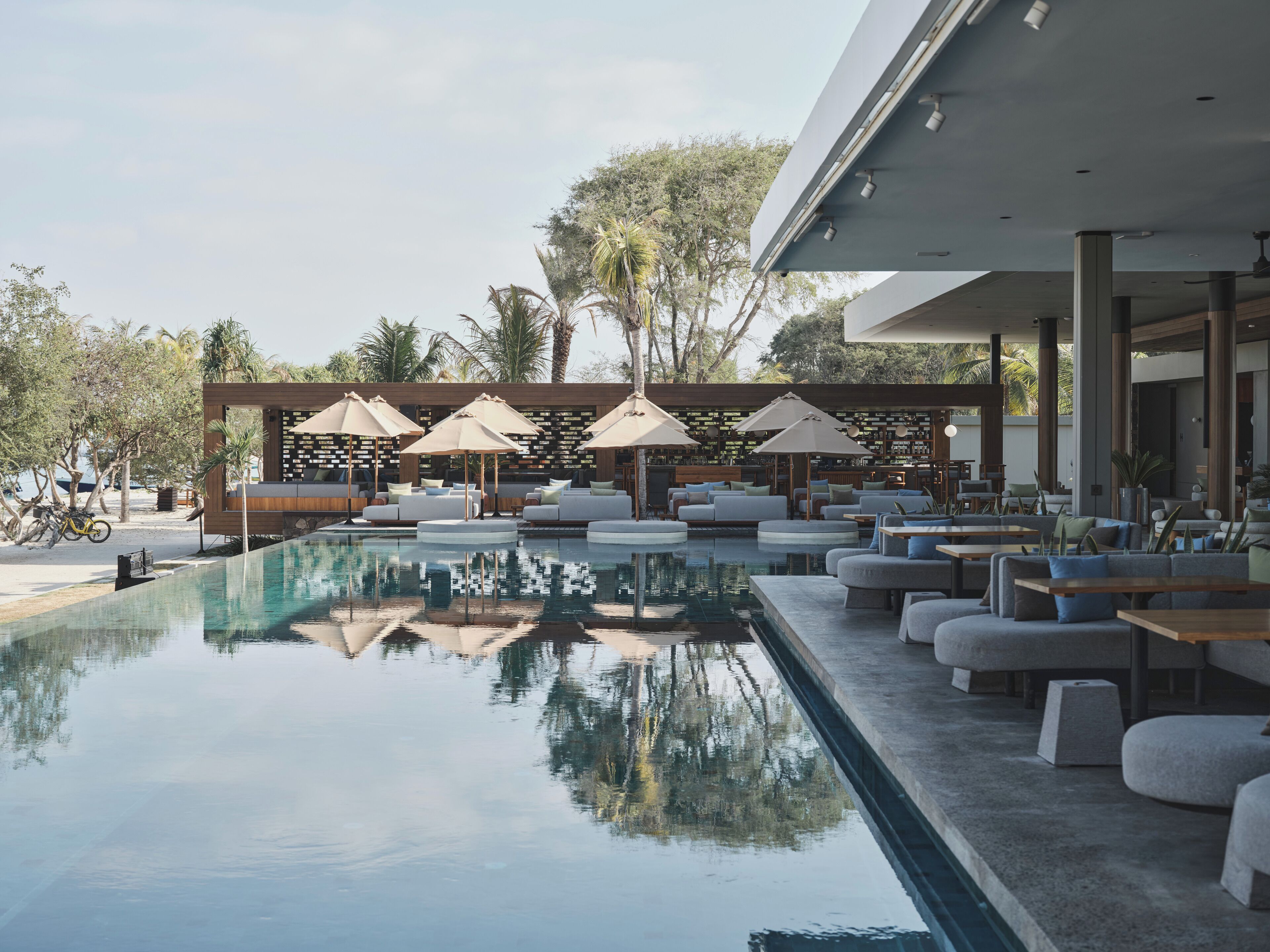 A poolside area with lounge chairs and umbrellas, a bar, and a view of the surrounding landscape.