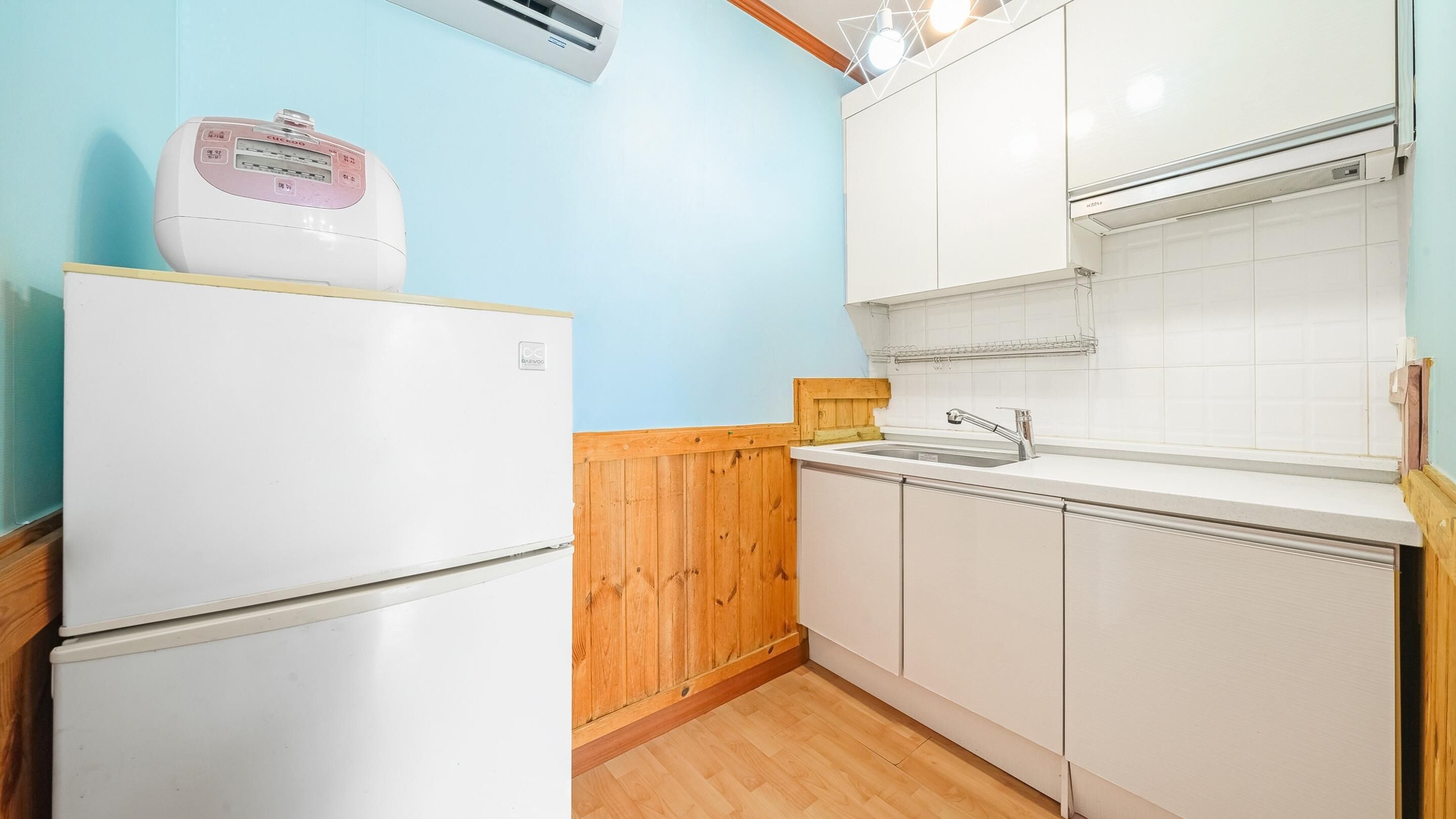 Una cocina compacta con refrigerador blanco, armarios de madera y un lavamanos integrado.