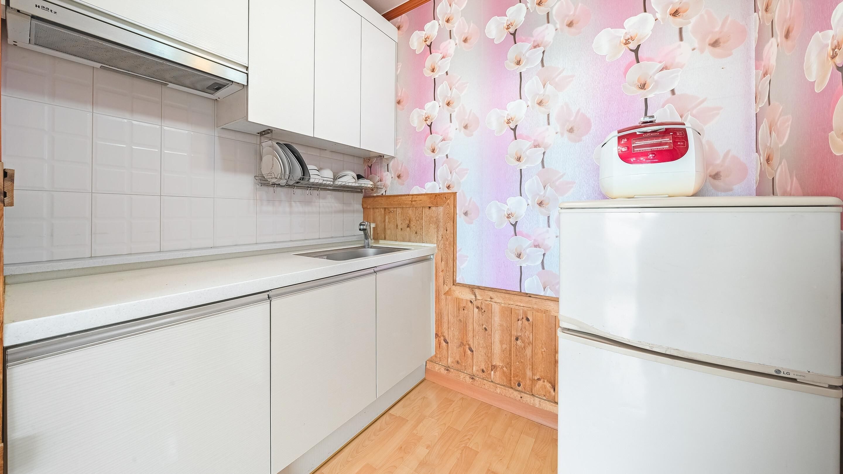 Una cocina con armarios blancos, un lavamanos y un refrigerador blanco.