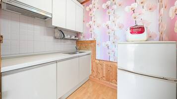 Una cocina con armarios blancos, un lavamanos y un refrigerador blanco.