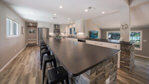 A spacious kitchen with a large island, built-in appliances, and a stone accent wall. - NB Lakefront Getaway*Luxury on Lake Dunlap (New Braunfels)