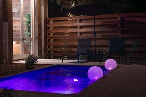 A swimming pool with a wooden deck and lounge chairs.