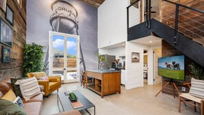 A spacious living area with a high ceiling, a staircase, and a kitchen area. - 8Sages*Texas Forever*Sleeps 6*Private Plunge Pool (New Braunfels)