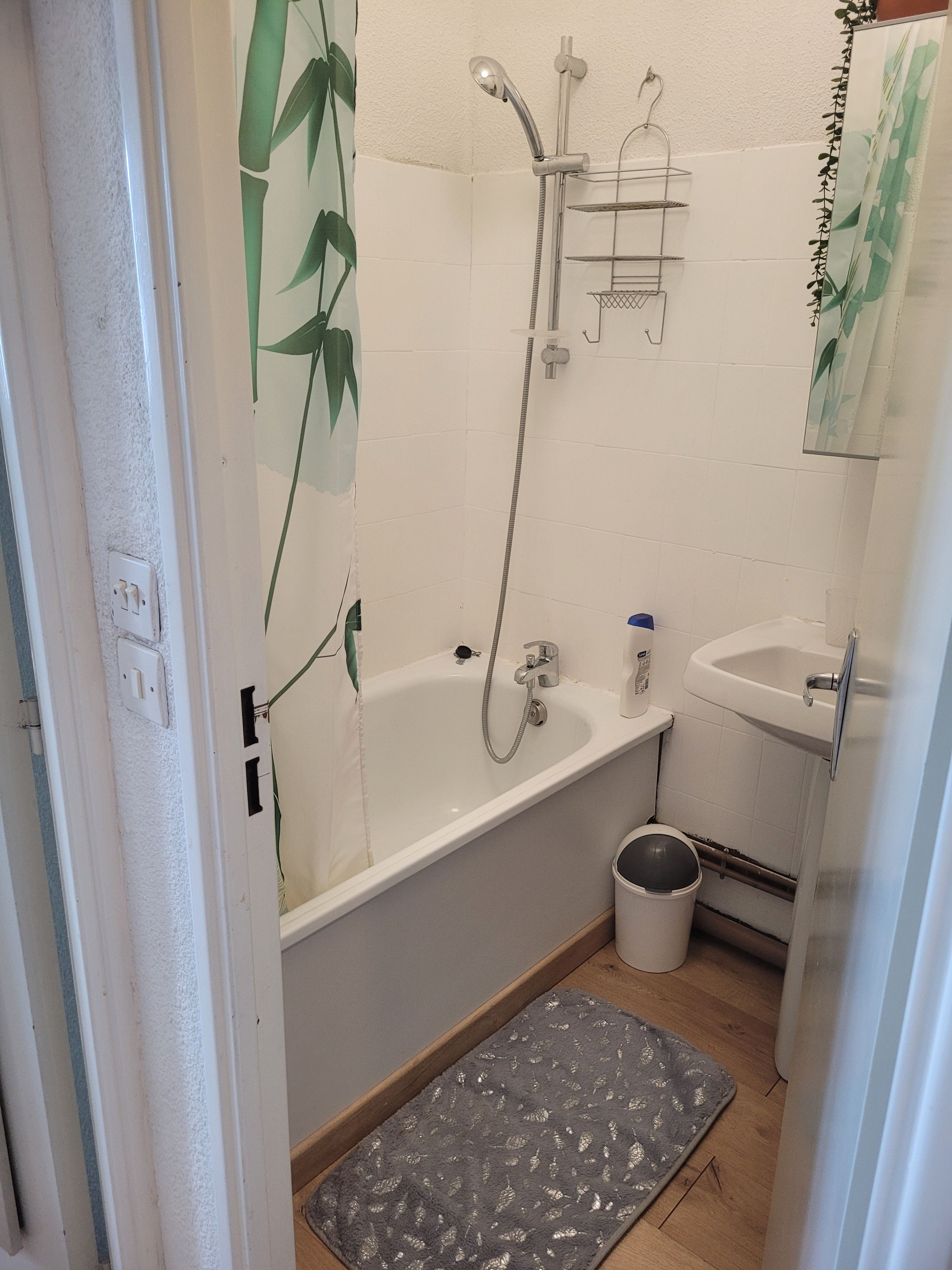 Une salle de bain équipée d’une baignoire, d’une douche, d’un lavabo et d’une petite poubelle.