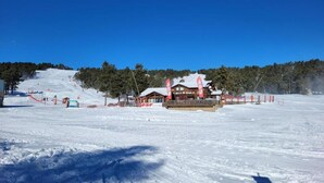 A snow-covered ski resort with a lodge featuring a wooden exterior and a snow-covered roof. - Appartement Rénové Avec une Magnifique vue (Font-Romeu-Odeillo-Via)