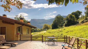 Une terrasse offrant une vue sur une colline verdoyante et une montagne au loin.