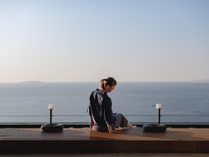 A person sitting on a wooden deck overlooking a body of water. - Atami Izusan KARAKU（ORIX HOTELS & RESORTS） (Atami)